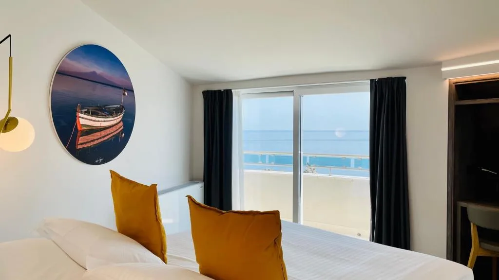 Dettaglio camera con vista mare dalla finestra e quadro con barca