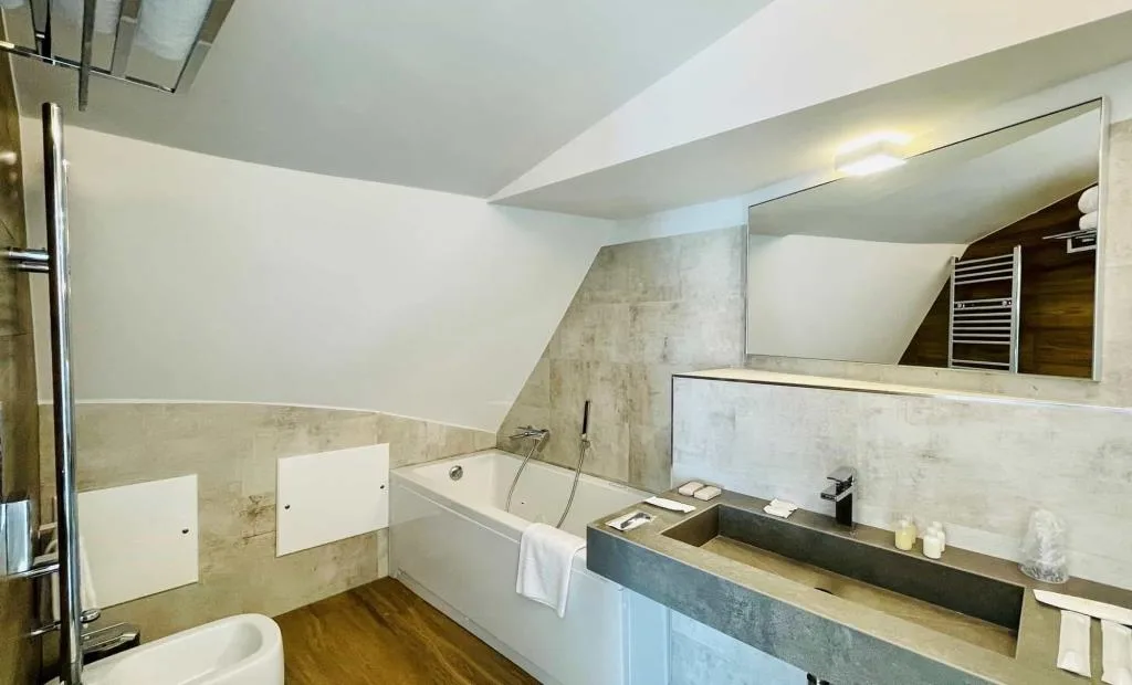 Bagno moderno con vasca, doppio lavabo in cemento e grande specchio