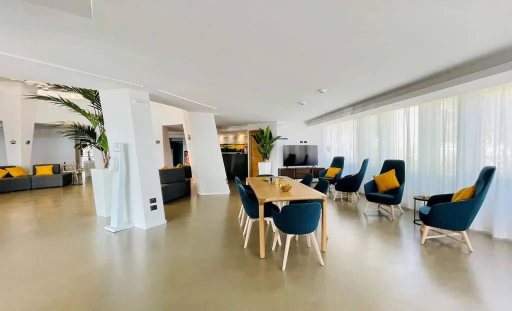 Sala comune con tavolo in legno e poltrone blu con cuscini gialli