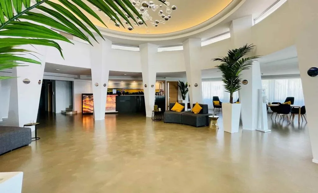 Hall dell'hotel con colonne bianche, divani grigi e lampadario a bolle