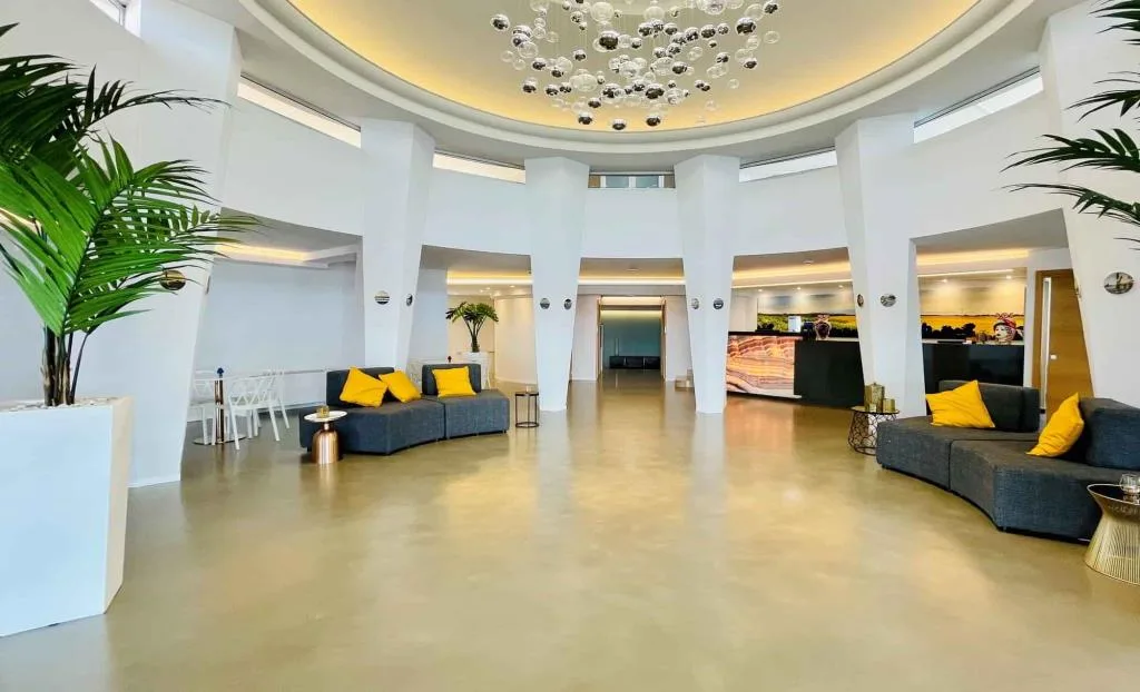 Ampia lobby luminosa con colonne, palme e grande lampadario decorativo