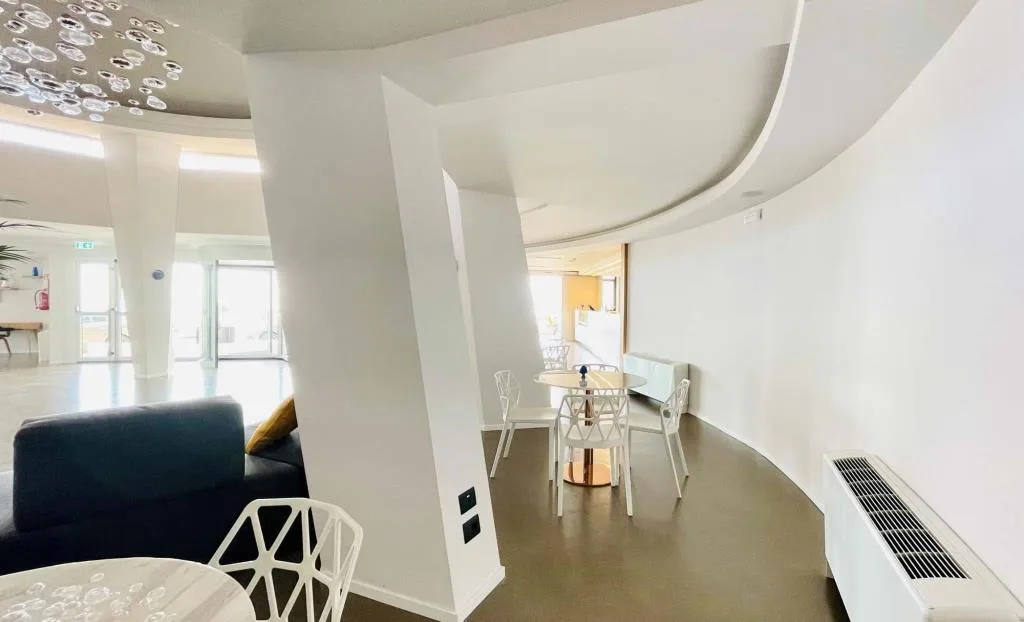 Zona relax con architettura circolare, tavolini e sedie bianche