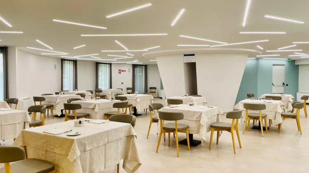 Sala ristorante con tavoli apparecchiati e illuminazione a linee luminose