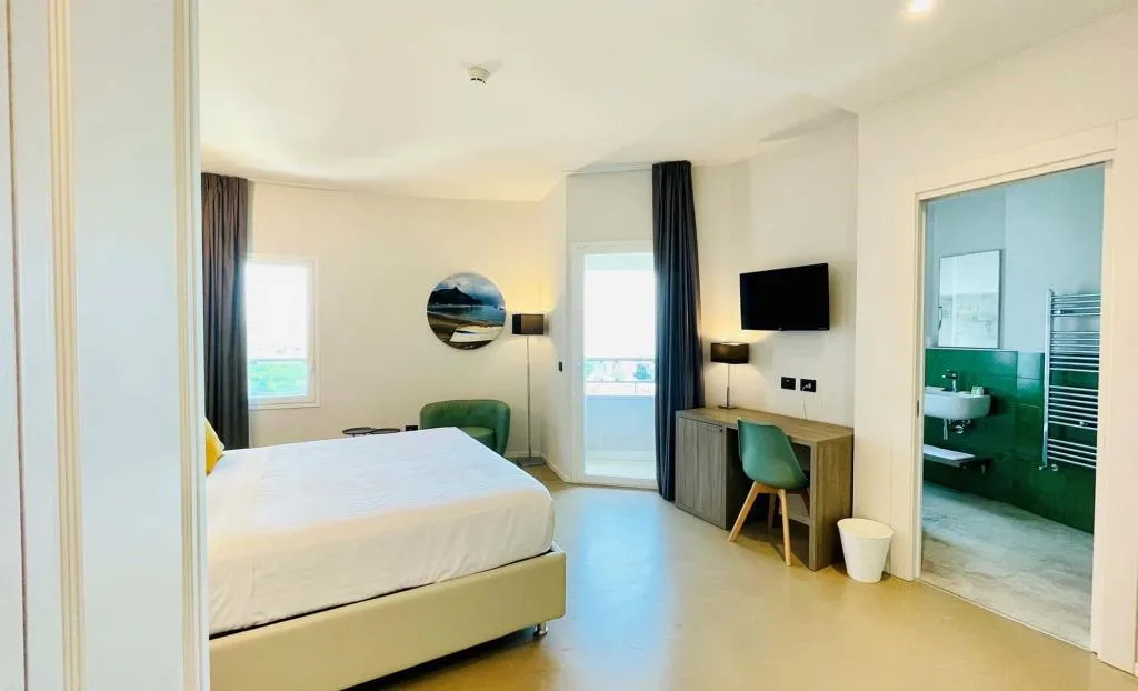 Camera con letto matrimoniale, balcone e bagno con piastrelle verdi