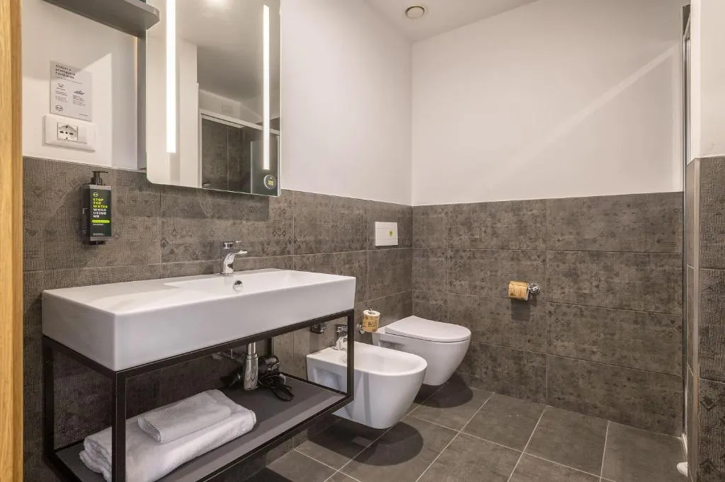 Bagno con ampio lavabo bianco, specchio illuminato, WC e bidet