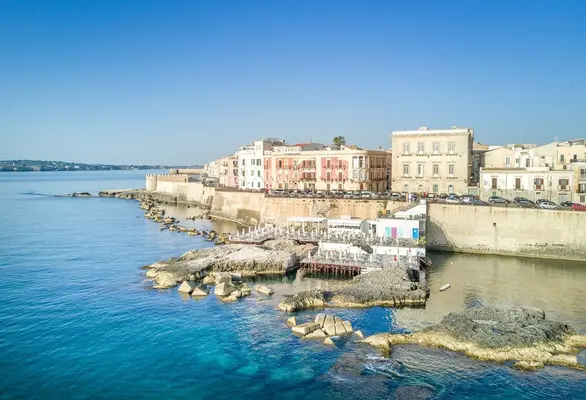 Veduta aerea della costa di Ortigia con edifici storici e mare cristallino