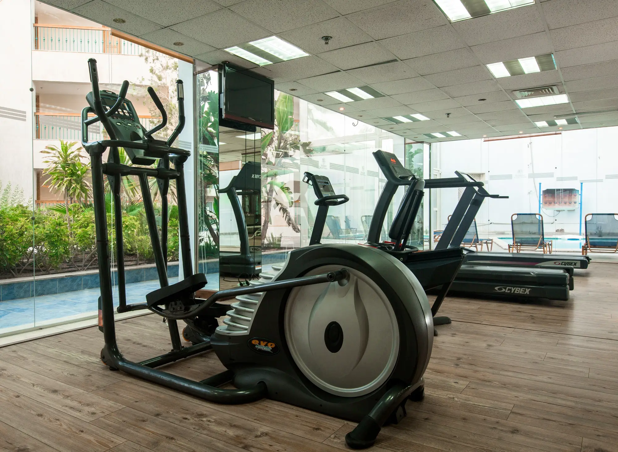 Sala fitness con attrezzatura cardio, ellittiche e tapis roulant vicino a grandi vetrate
