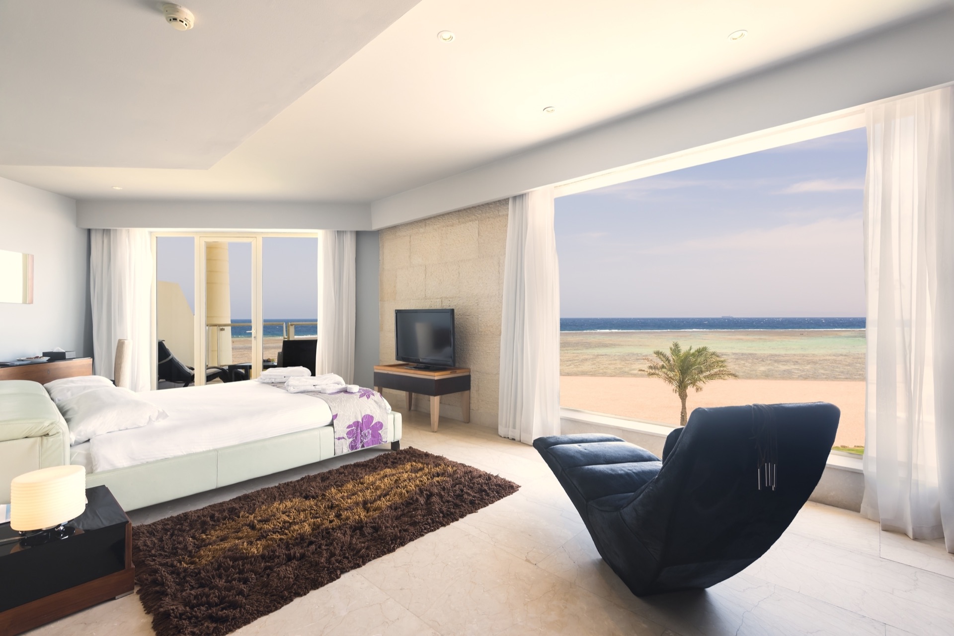 Camera luminosa con grande vetrata, poltrona e vista panoramica sul mare