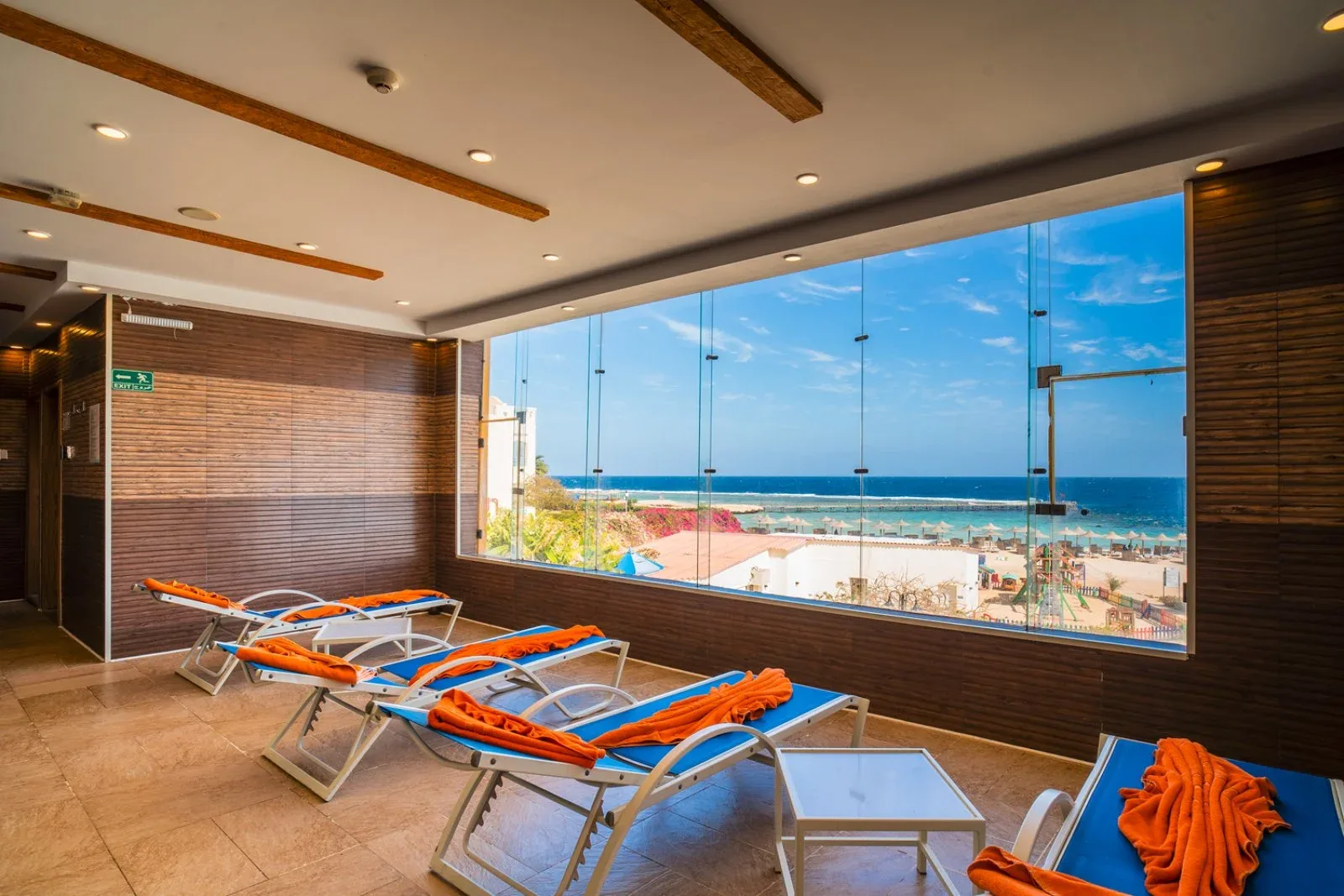 Area relax con lettini blu e grande vetrata affacciata sul mare