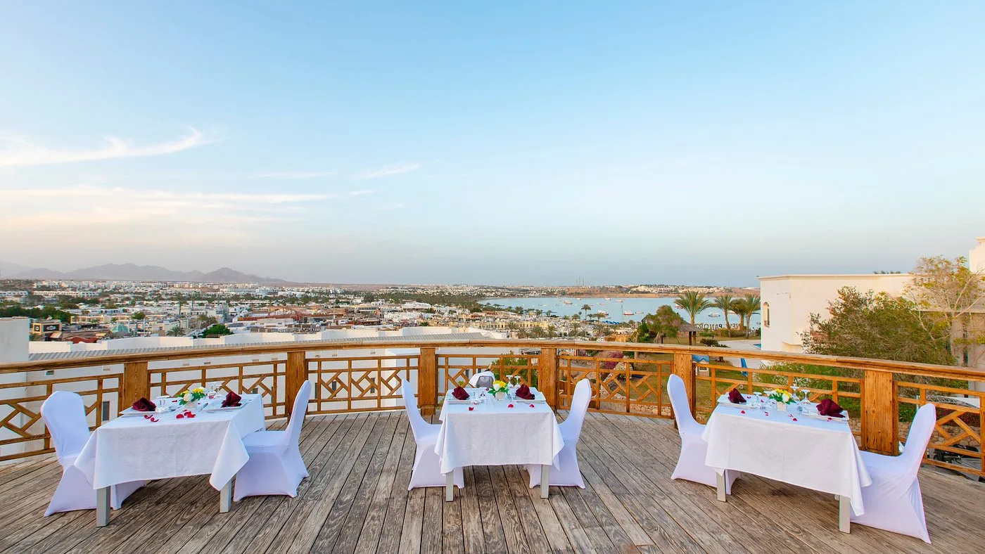 Terrazza con tavoli apparecchiati per cena romantica e vista sulla baia
