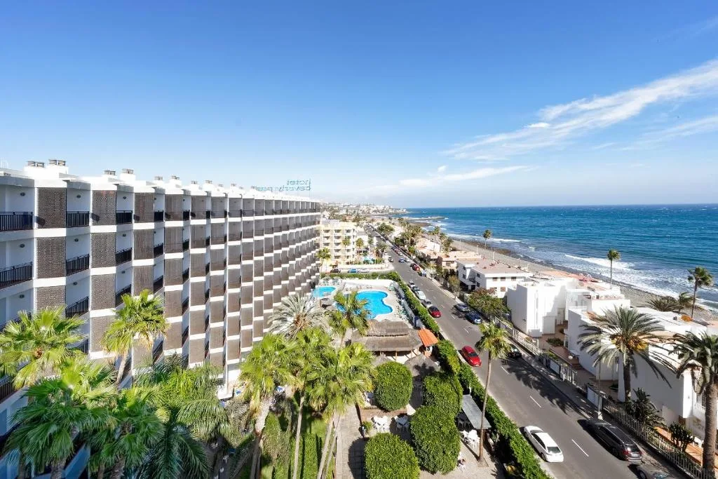 Vista panoramica dell'hotel sulla costa con piscina, palme, strada e mare