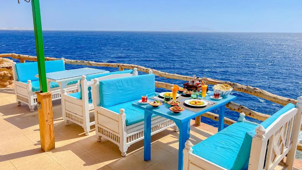 Terrazza sul mare con colazione servita su tavolo azzurro e divanetti con cuscini